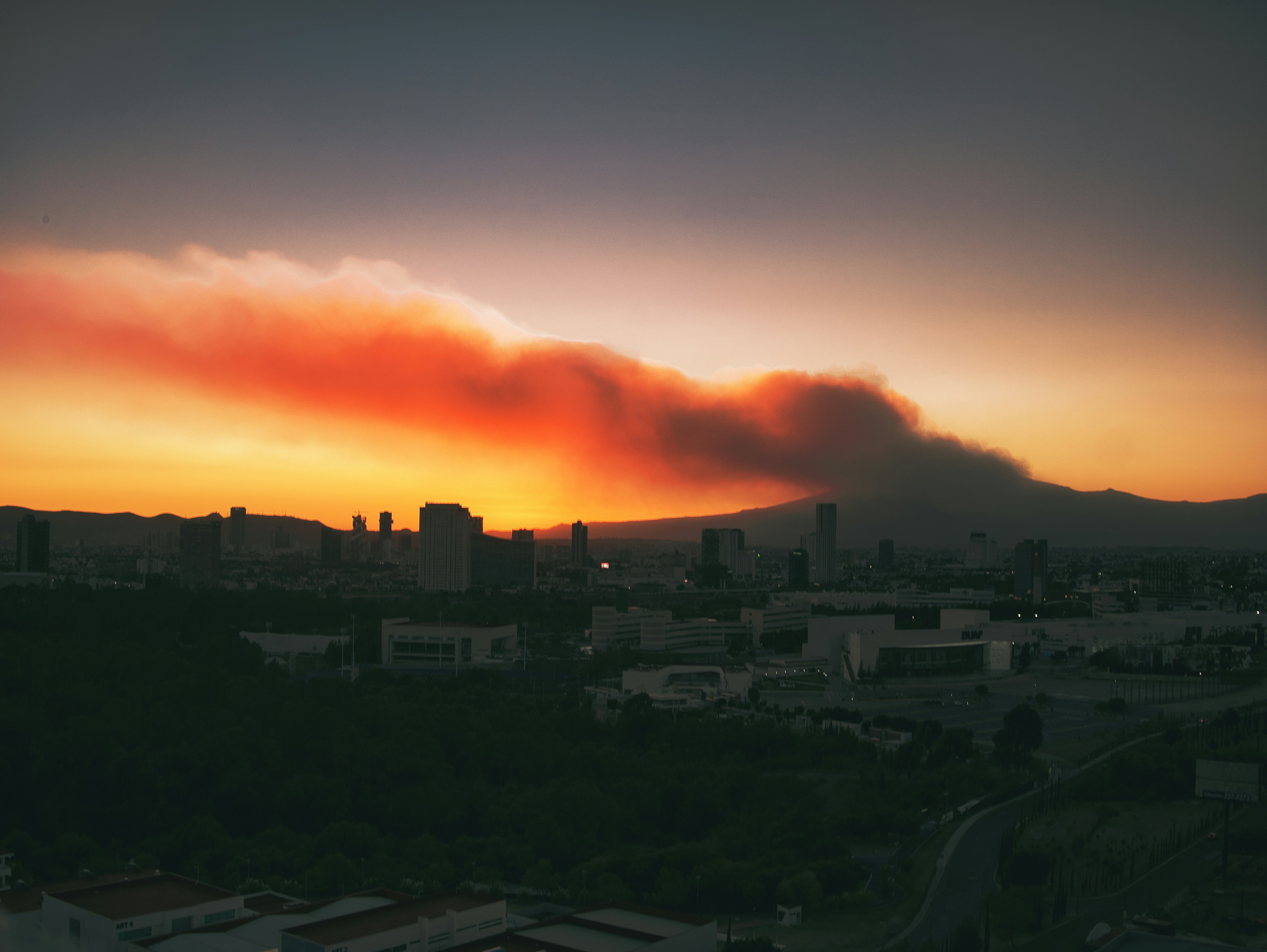 a large cloud of smoke is in the sky over a city